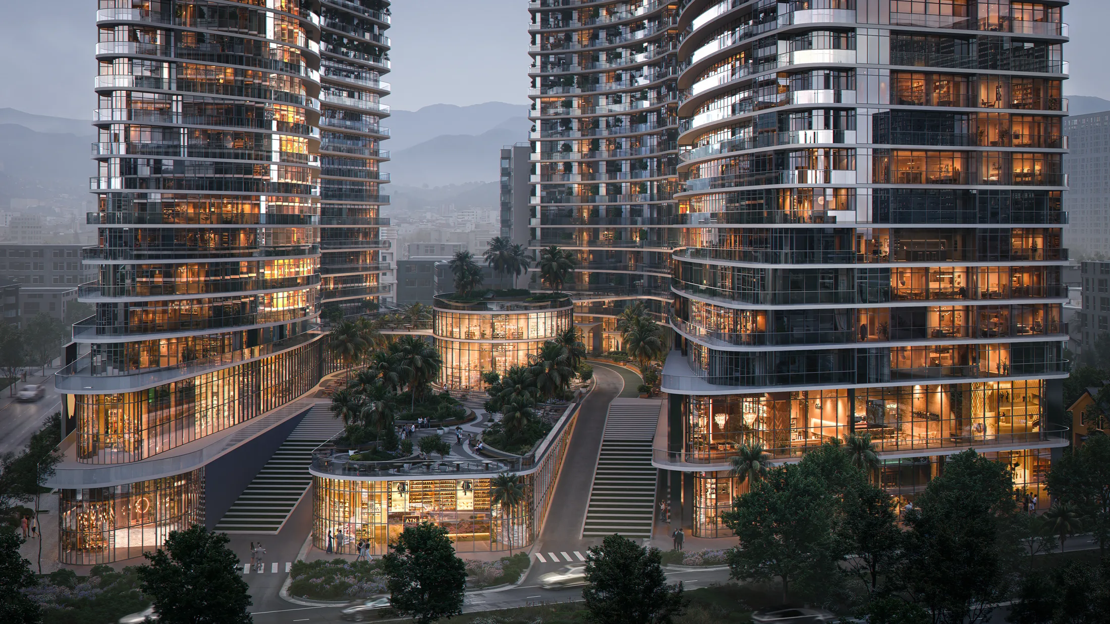 OPUS Signature at dusk &mdash; the lit street-level retail and the two towers against the Caucasus foothills